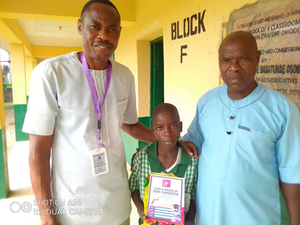 The coordinator of JATOH foundation in a group photo with the head teacher and one of the students